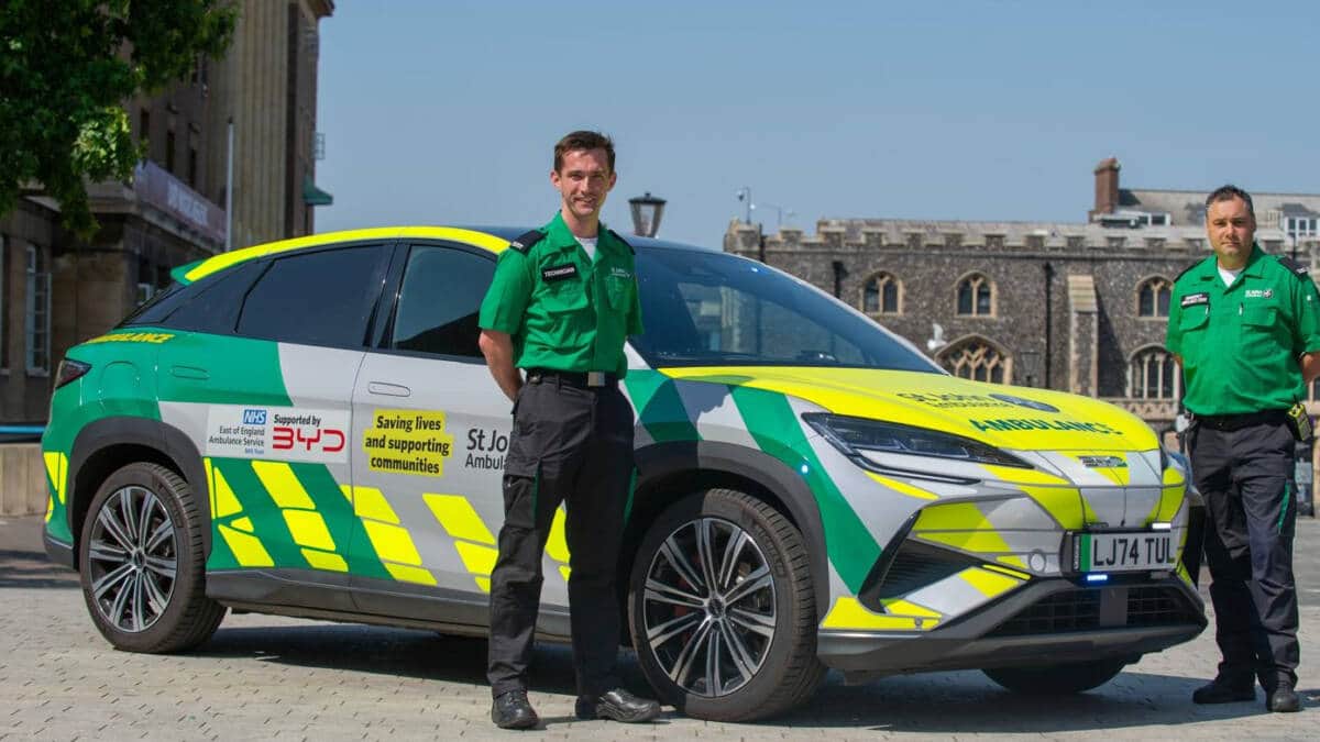 Two people in security uniforms beside a BYD SEALION 7 electric vehicle