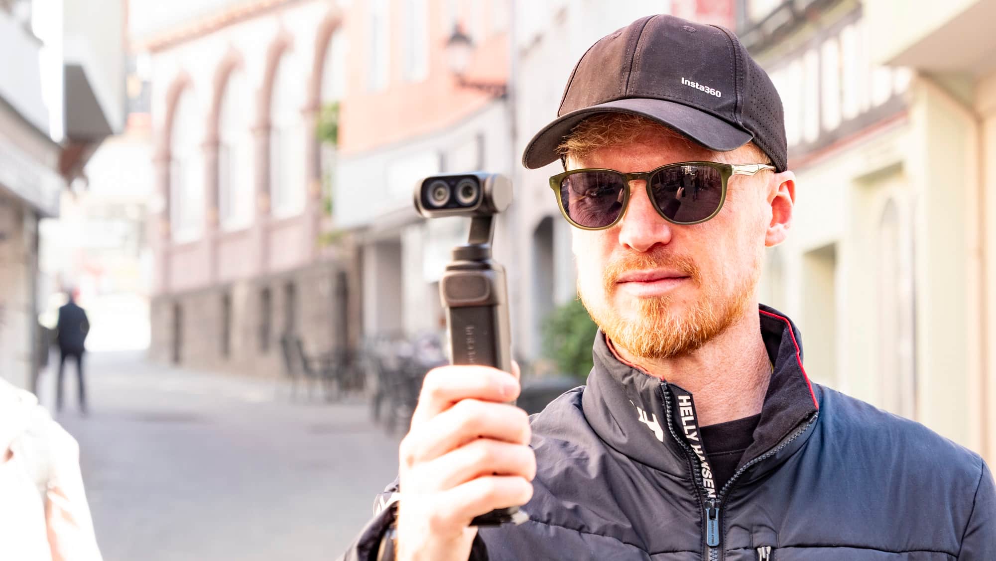 Man holding the Insta360 Luna Ultra vlogging camera on a sunny day in an old town