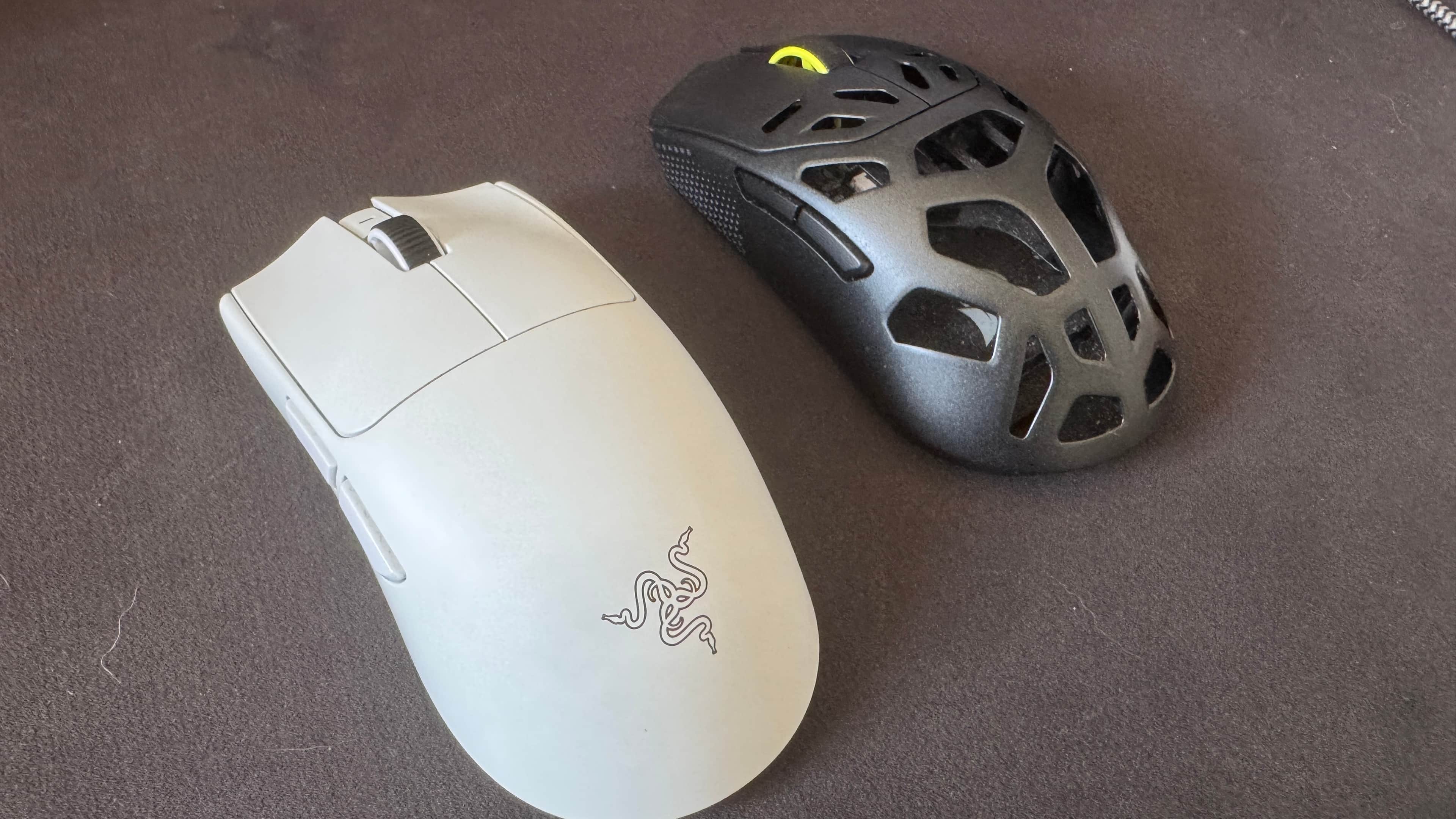 Two gaming mice next to each other on a black mousepad