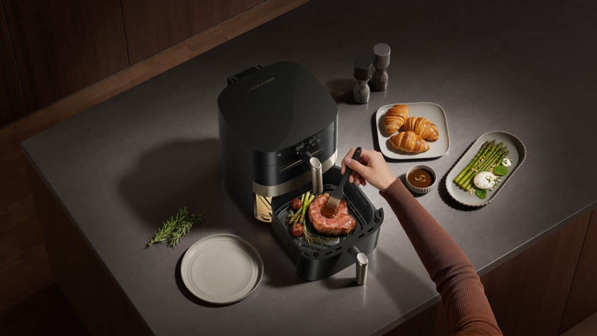 Person cooking a steak with vegetables and bread in an air fryer