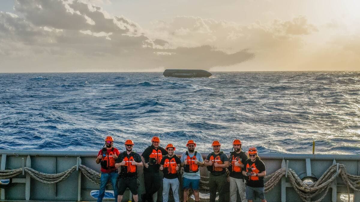 Un grupo de personas con chalecos salvavidas y cascos en la cubierta de un barco