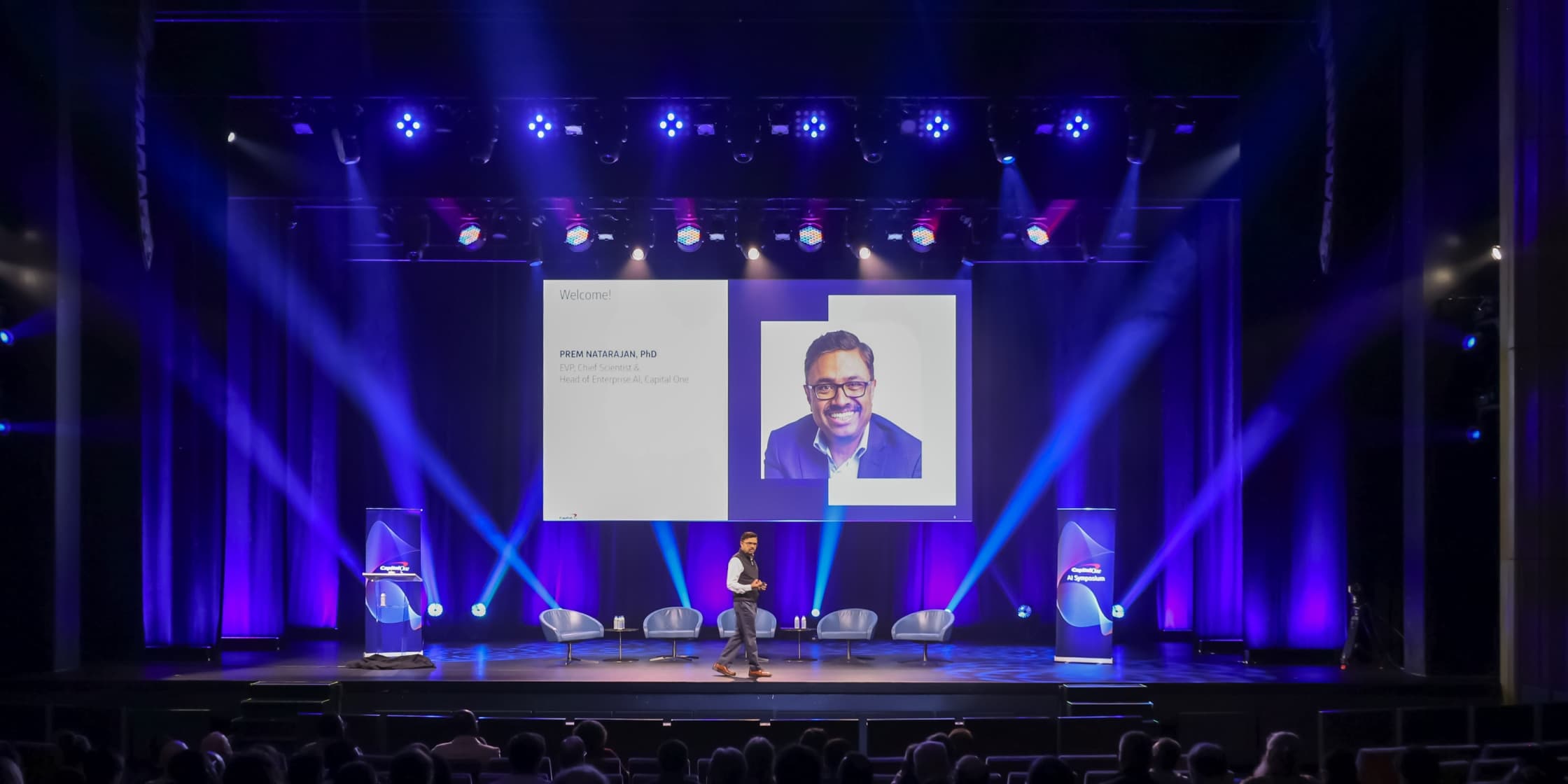 Prem Natarajan, PhD, presenta una sesión en el escenario durante el simposio inaugural de IA de Capital One