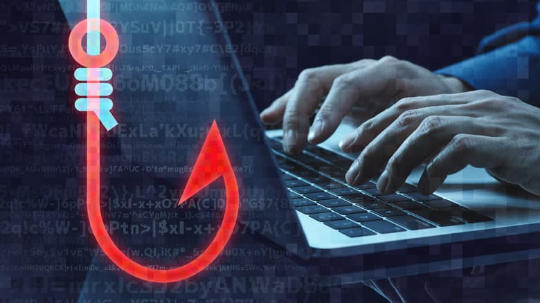 Rendered graphic of a fishing hook overlaid on a close-up of hands typing on a laptop keyboard.