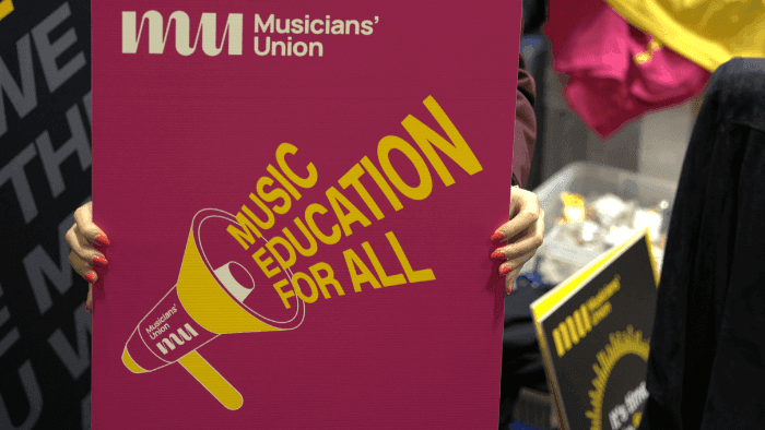 A musician's union branded placard reading 'music education for all'