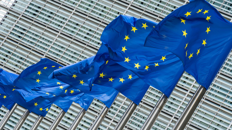 European Union flags waving in front of the European Commission headquarters.