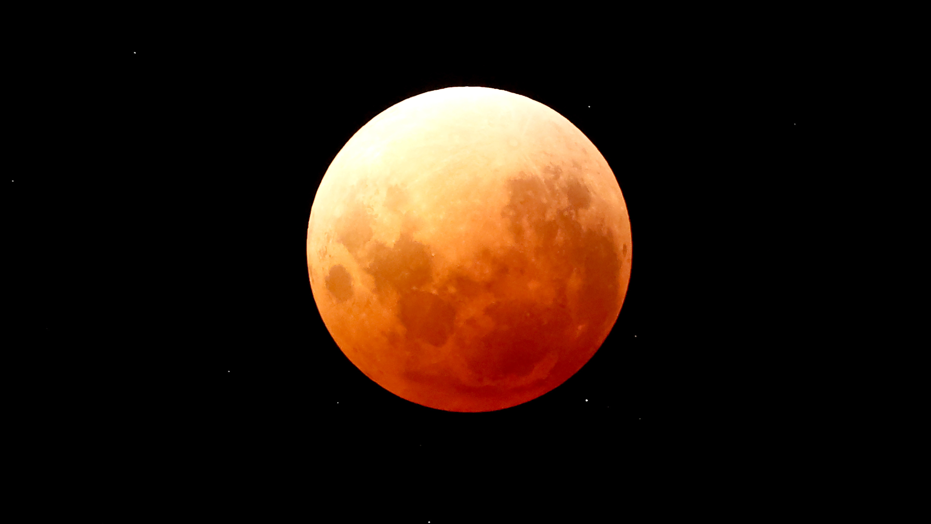 An orange-red full moon is pictured in a black sky during a total lunar eclipse.