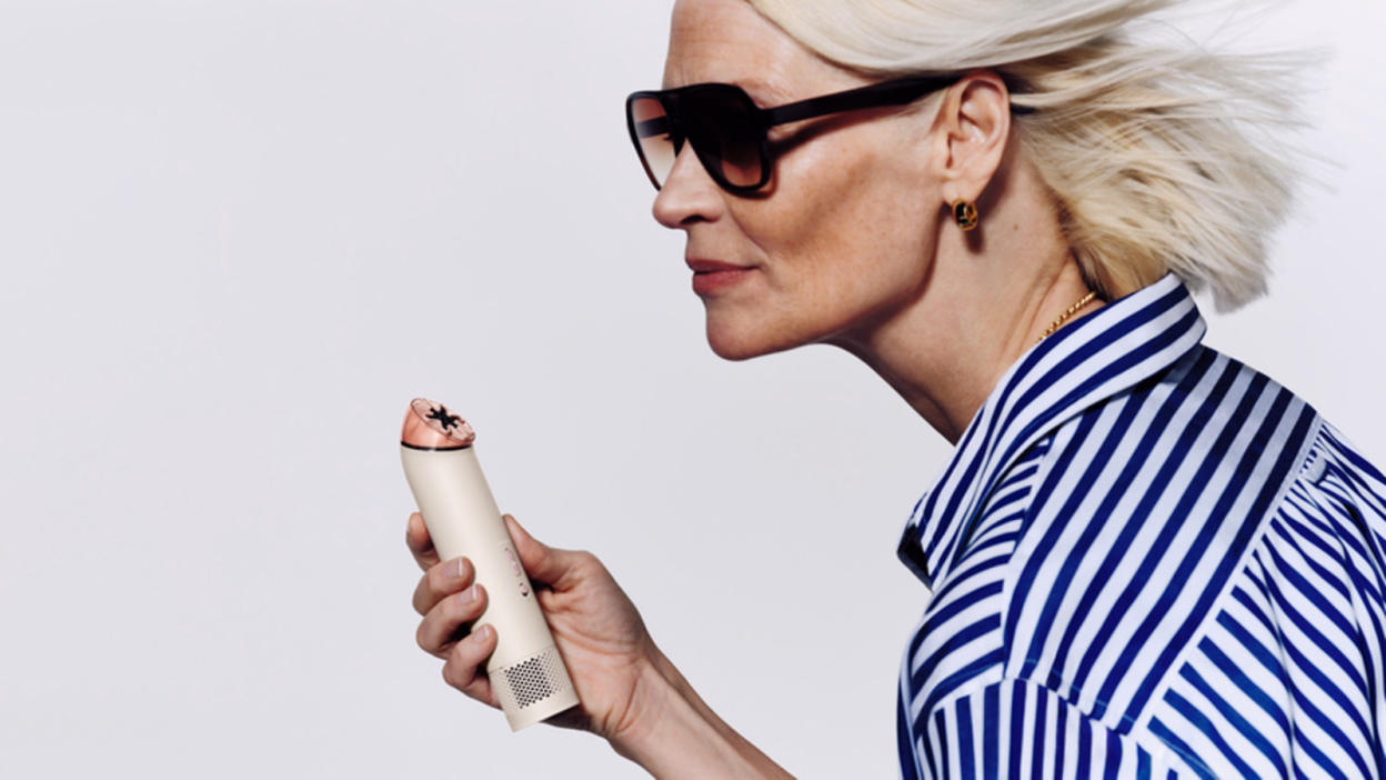 Woman with short blonde hair wearing sunglasses holding Dyson Airwrap