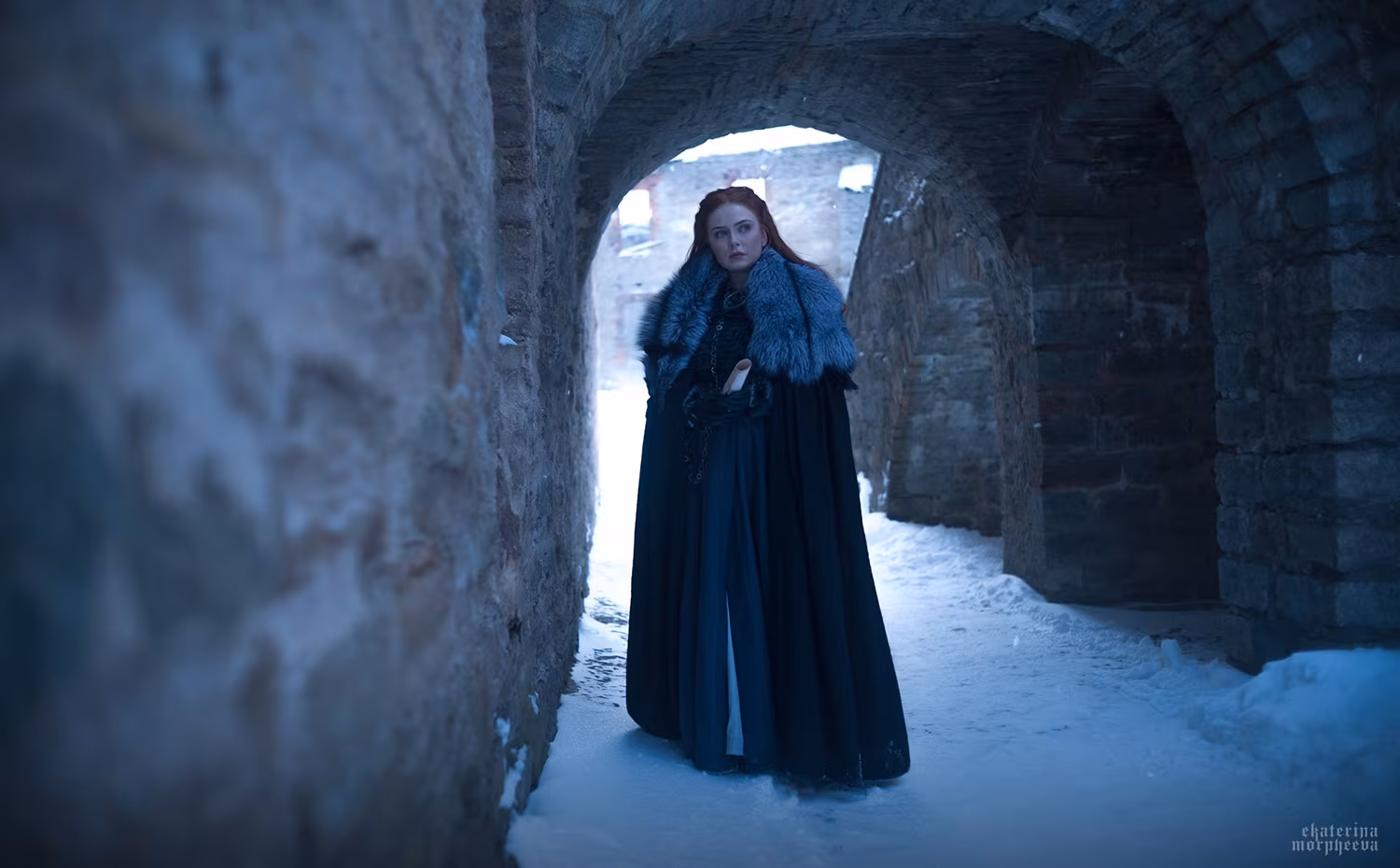 Woman in long black skirt next to stone archway from TV show cosplay