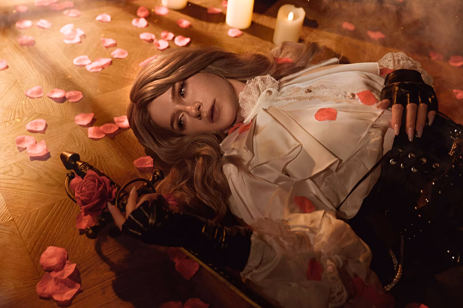 Woman with brown hair lying on floor surrounded by pink petals and candles