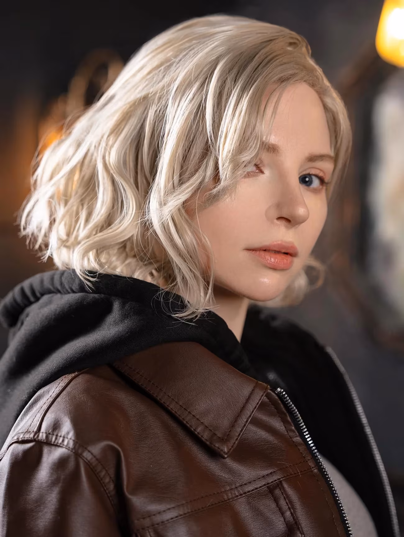 Girl with short blonde waves and blue eyes wearing a jacket