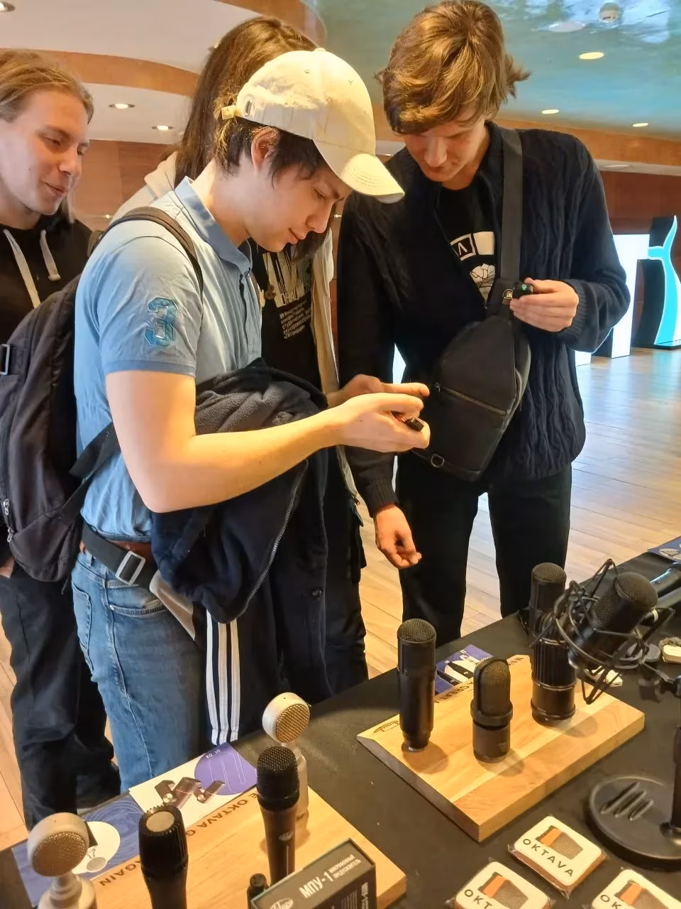 Three people examine microphones at the Octava DM product booth