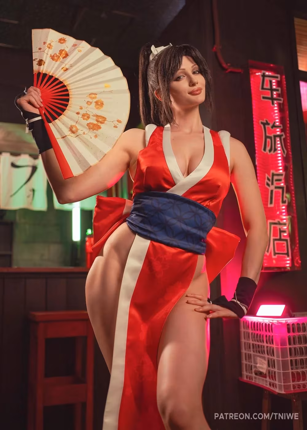 Model in Mai Shiranui cosplay with red dress and fan