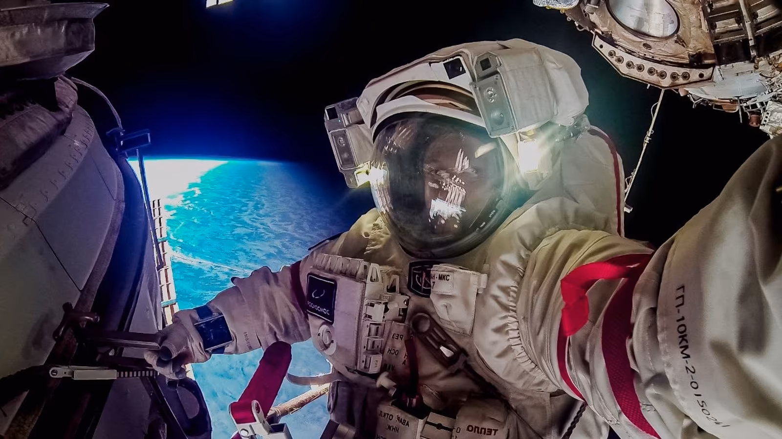 Russian cosmonaut during spacewalk outside ISS with suit and tablet