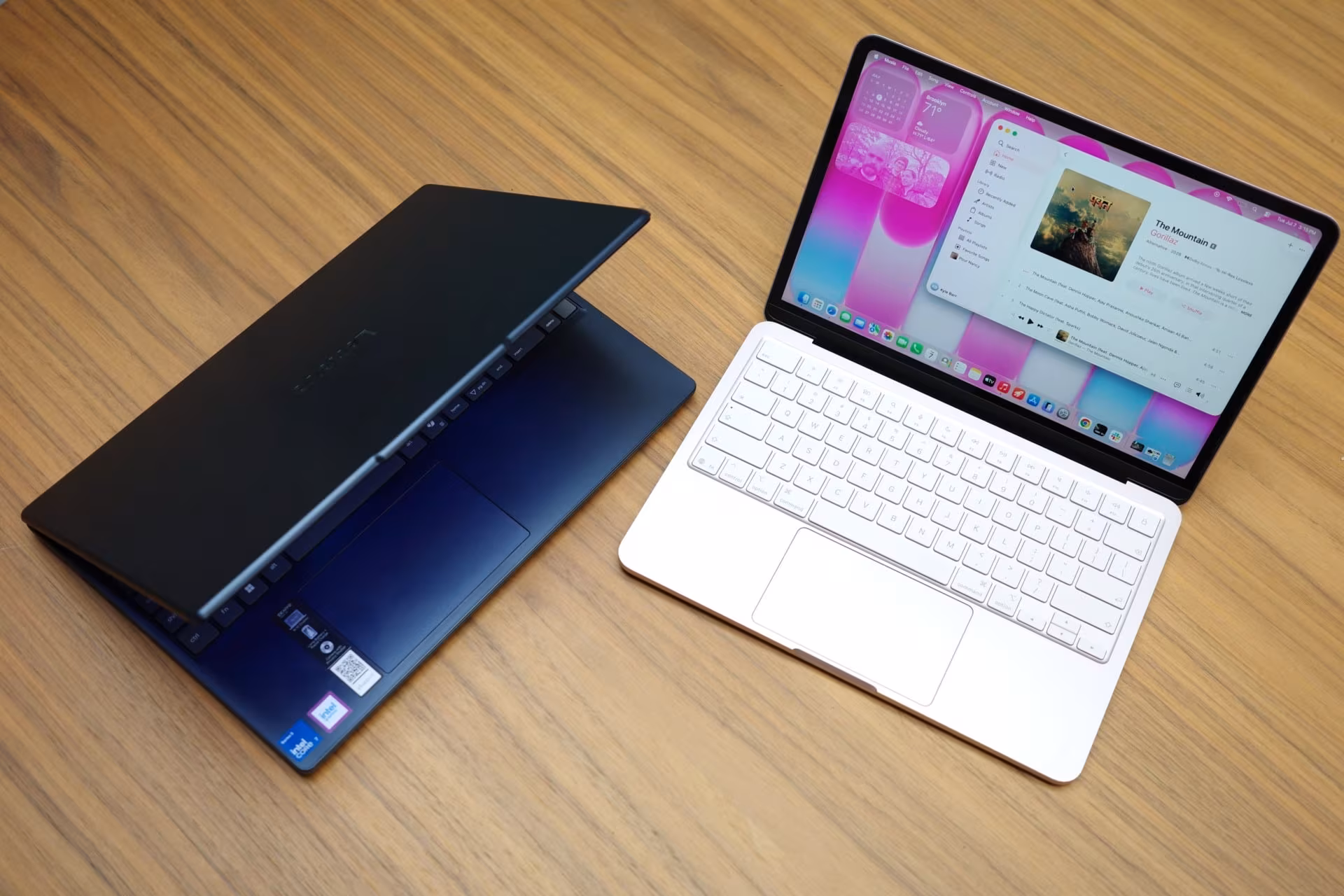 Lenovo laptop on wooden surface next to MacBook Neo